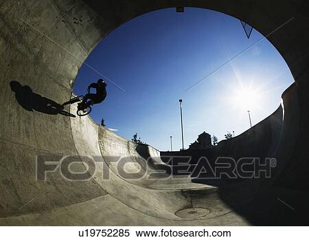 Stock Photography - Mountain biker in concrete pipe, Calgary, Shaw Millenium Park. Fotosearch