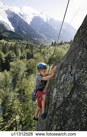 Stock Photograph - Young kid climbing in front of Mont Blanc, Les Gaillands, Chamonix. Fotosearch