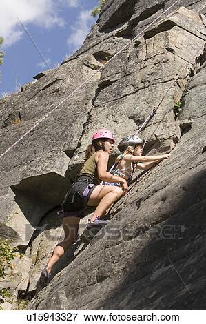 Stock Photo - Young woman climbing with daughter (age 7) up granite cliff at Stone Hills near Rexford, Montana, USA. Fotosearch