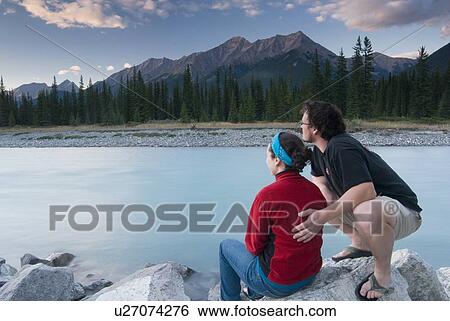 A couple enjoys the sunset from the banks of The Kootenay River in Kootenay National Park View Large Photo Image Stock Photograph - A couple enjoys the sunset from the banks of The Kootenay River in Kootenay National Park. Fotosearch