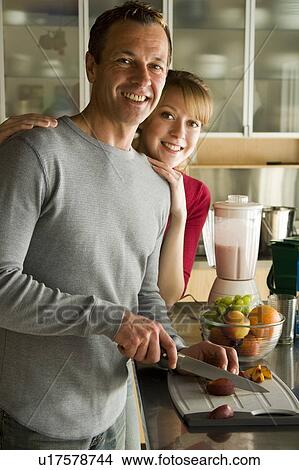 Picture - Couple cutting organic fruit for smoothie, Winnipeg, Canada. Fotosearch