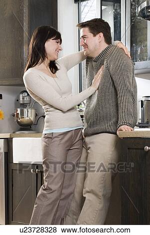 Stock Photo - Couple in kitchen. Home has recovered/recycled cupboards and hardwood floors, Winnipeg, Canada. Fotosearch
