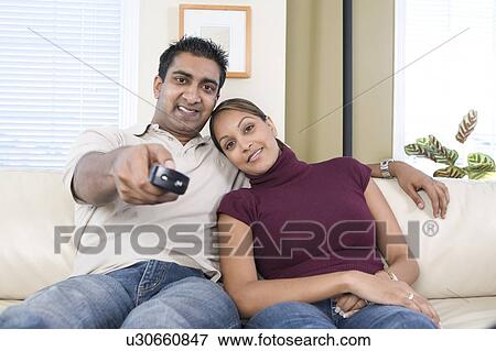 Man and woman on sofa with remote control, Winnipeg, Canada View Large Photo Image Stock Photo - Man and woman on sofa with remote control, Winnipeg, Canada. Fotosearch