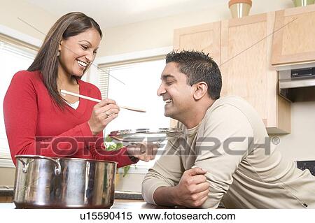 Stock Photography - Woman offers man spoon for him to taste, Winnipeg, Canada. Fotosearch