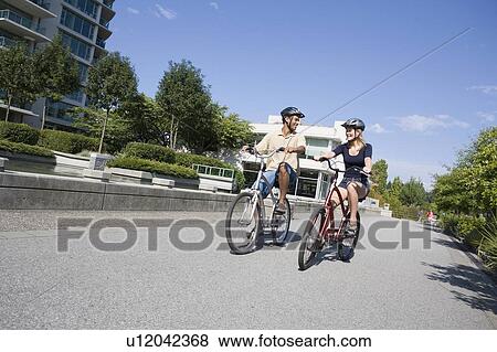 Young Couple Ride Bicycles on city bike path, Vancouver, British Columbia View Large Photo Image Stock Photo - Young Couple Ride Bicycles on city bike path, Vancouver, British Columbia. Fotosearch