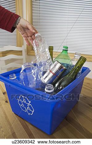 Stock Image - Homemaker taking out "Blue Bin" full of bottles and cans for recycling.. Fotosearch