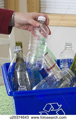 Stock Image - Homemaker taking out "Blue Bin" full of bottles and cans for recycling.. Fotosearch