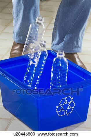Stock Image - Homemaker throwing bottles into a "Blue Bin" for recycling.. Fotosearch