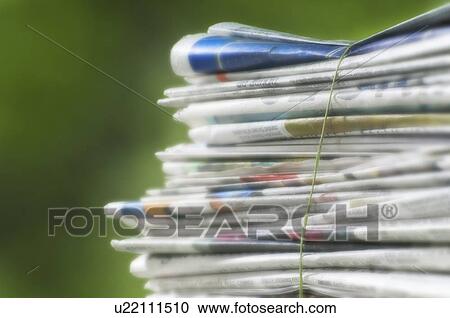 Stock Image - Newspapers tied into a pile for the recycle bin.. Fotosearch