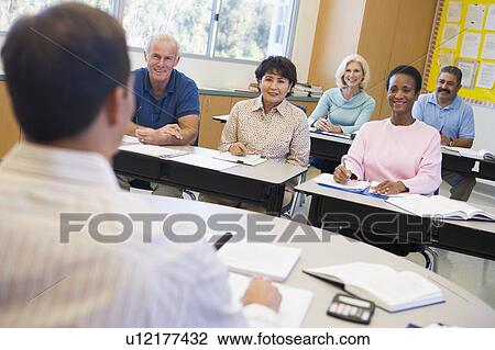 Stock Image - Adult students in class with teacher (selective focus). Fotosearch