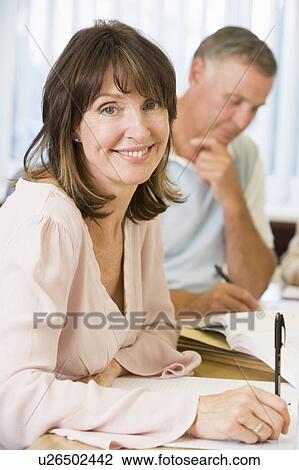 Stock Image - Adult students studying at table (selective focus). Fotosearch