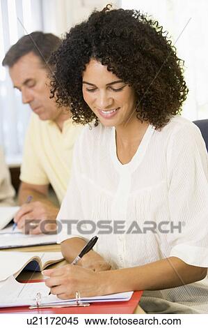 Stock Photography - Adult students studying at table (selective focus). Fotosearch