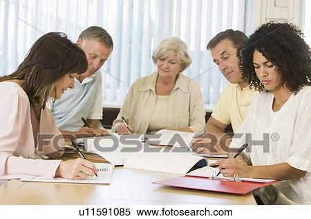 Stock Photography - Five adult students studying at table (depth of field). Fotosearch