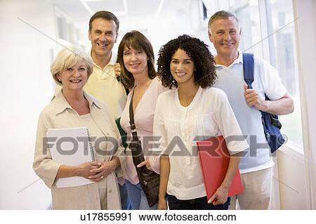 Stock Image - Five people standing in corridor with books (high key). Fotosearch