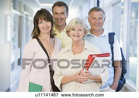 Stock Photo - Four people standing in corridor with books (high key). Fotosearch