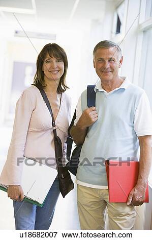 Stock Photo - Man and woman standing in corridor with books (high key). Fotosearch