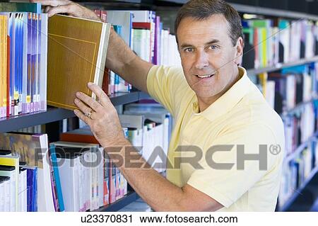 Man in library pulling book off a shelf (depth of field) View Large Photo Image Stock Image - Man in library pulling book off a shelf (depth of field). Fotosearch