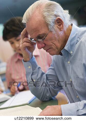 Stock Photo - Man sitting near woman in library with books and notepads (selective focus). Fotosearch