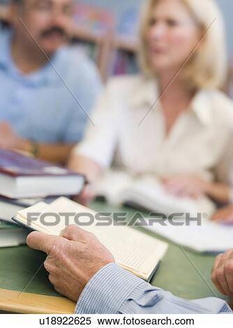 Stock Photography - Three people sitting in library with books and notepads (selective focus). Fotosearch