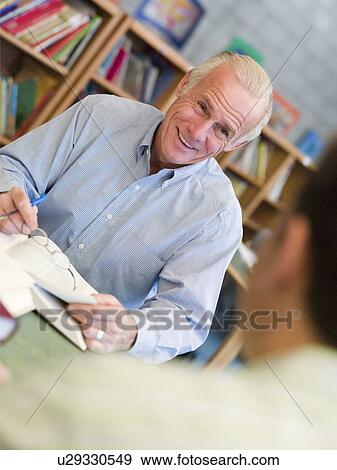 Stock Photo - Two men in library with notepads talking (selective focus). Fotosearch