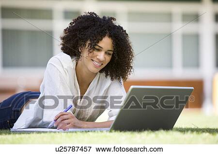 Woman lying on lawn of school with laptop View Large Photo Image Stock Photo - Woman lying on lawn of school with laptop. Fotosearch