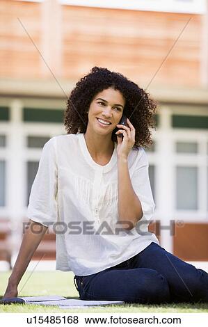 Stock Photo - Woman on lawn of school using cellular phone. Fotosearch