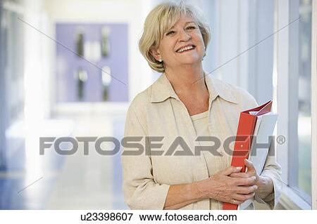 Woman standing in corridor with books (high key) View Large Photo Image Stock Photo - Woman standing in corridor with books (high key). Fotosearch