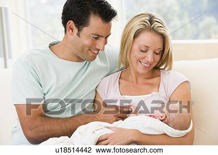 Stock Image - Couple in living room with baby smiling. Fotosearch
