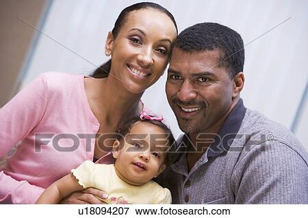 Stock Photo - Couple indoors with baby smiling. Fotosearch