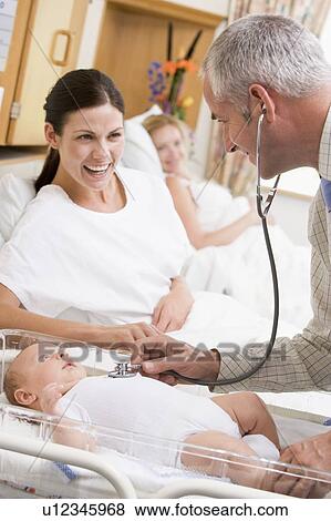 Stock Photo - Doctor checking baby's heartbeat with new mother watching and smiling. Fotosearch