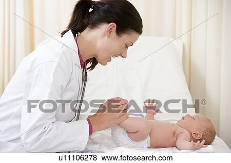 Stock Photo - Doctor giving checkup to baby in exam room smiling. Fotosearch