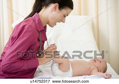 Doctor giving checkup to baby in exam room smiling View Large Photo Image Stock Photo - Doctor giving checkup to baby in exam room smiling. Fotosearch