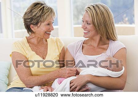 Stock Image - Grandmother and mother in living room with baby smiling. Fotosearch