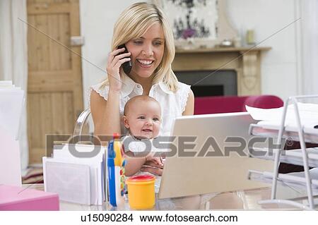 Mother and baby in home office with laptop and telephone View Large Photo Image Picture - Mother and baby in home office with laptop and telephone. Fotosearch