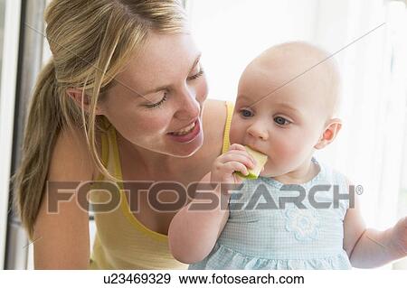 Mother and baby in kitchen eating apple View Large Photo Image Stock Photo - Mother and baby in kitchen eating apple. Fotosearch
