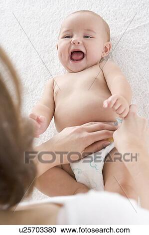 Mother changing baby's diaper indoors View Large Photo Image Stock Image - Mother changing baby's diaper indoors. Fotosearch