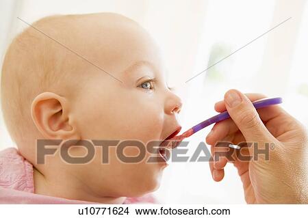 Picture - Mother feeding baby food to baby. Fotosearch