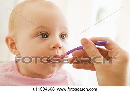 Stock Photo - Mother feeding baby food to baby. Fotosearch