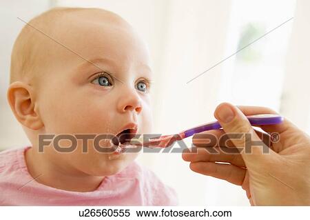 Stock Photography - Mother feeding baby food to baby. Fotosearch