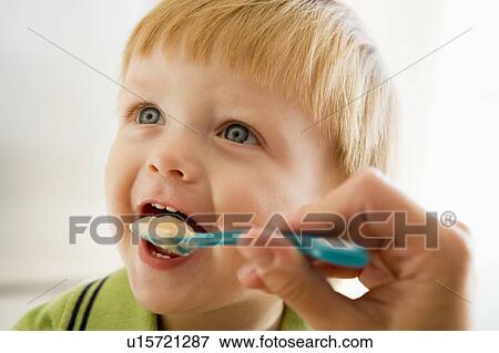 Mother feeding young boy baby food View Large Photo Image Stock Photo - Mother feeding young boy baby food. Fotosearch