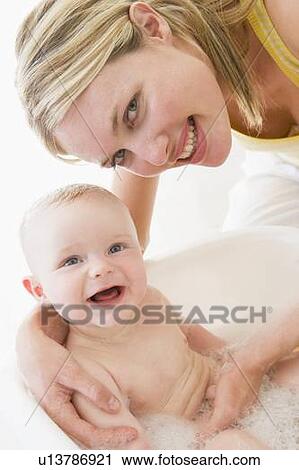 Stock Image - Mother giving baby bubble bath smiling. Fotosearch