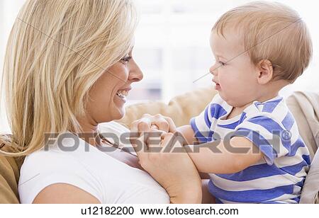 Stock Image - Mother in living room holding baby smiling. Fotosearch