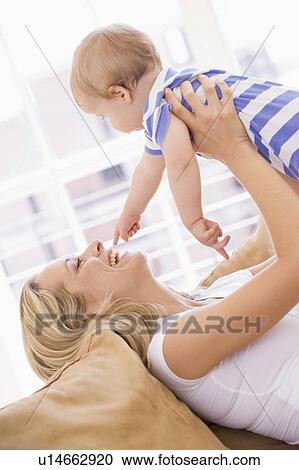 Mother in living room holding baby smiling View Large Photo Image Stock Image - Mother in living room holding baby smiling. Fotosearch
