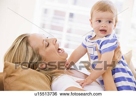 Stock Photograph - Mother in living room holding baby smiling. Fotosearch