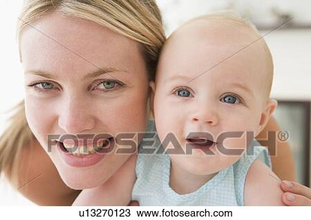 Mother in living room with baby smiling View Large Photo Image Stock Image - Mother in living room with baby smiling. Fotosearch