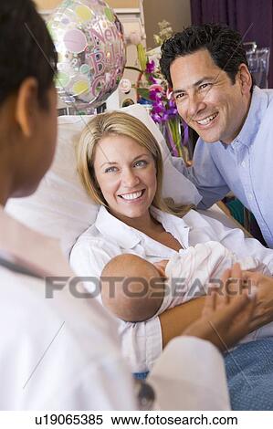 Stock Photography - New parents with baby talking to doctor and smiling. Fotosearch