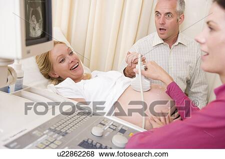 Pregnant woman getting ultrasound from doctor with husband watching View Large Photo Image Stock Photo - Pregnant woman getting ultrasound from doctor with husband watching. Fotosearch