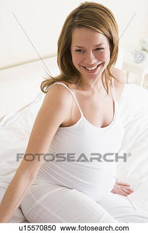 Pregnant woman sitting in bed smiling View Large Photo Image Stock Image - Pregnant woman sitting in bed smiling. Fotosearch