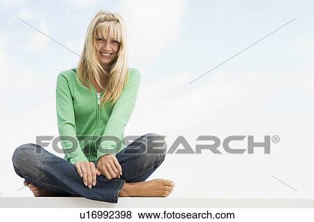 Stock Photo - Blonde woman in a green sweater sitting outdoors. Fotosearch