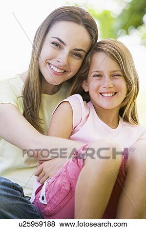 Stock Photo - Woman and young girl outdoors embracing and smiling. Fotosearch